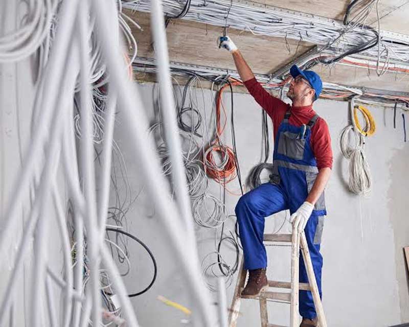 Électricien qualifié intervenant sur un tableau électrique dans le <a href=